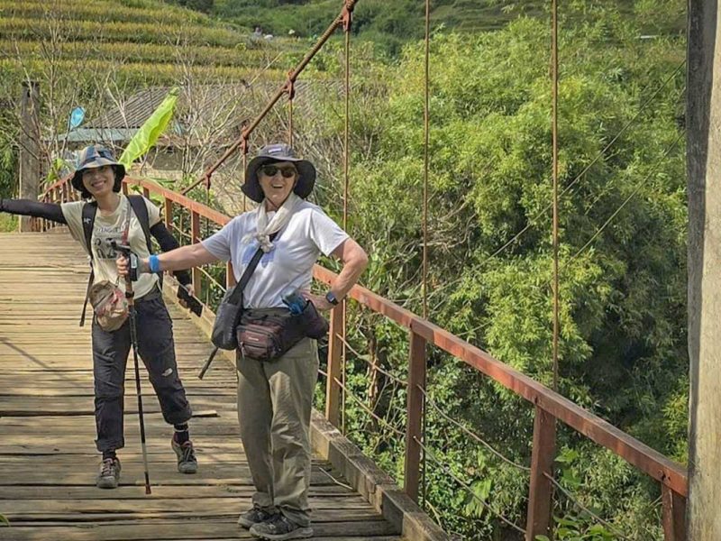 Mu Cang Chai trekking tour with two travelers crossing a wooden suspension bridge in the mountains
