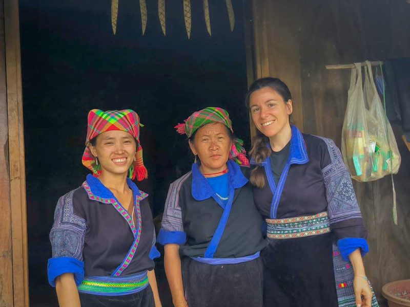 Mu Cang Chai tour cultural visit with a traveler posing with Hmong hosts in traditional clothing
