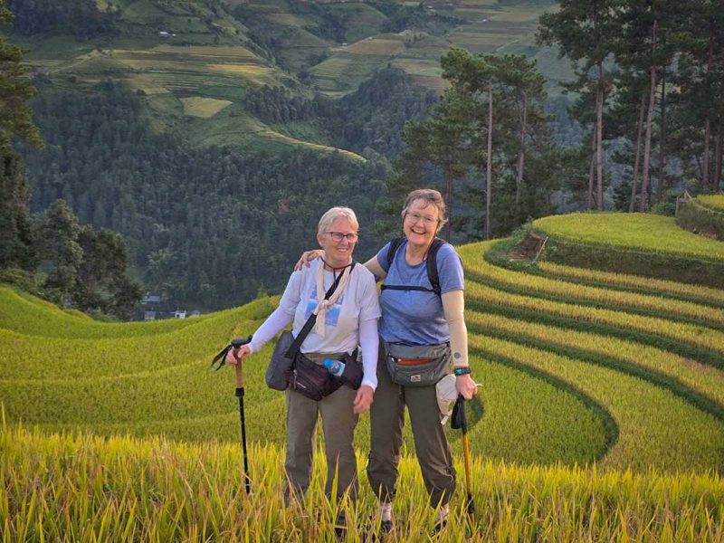 Mu Cang Chai trekking tour with two hikers standing among terraced rice fields at sunset