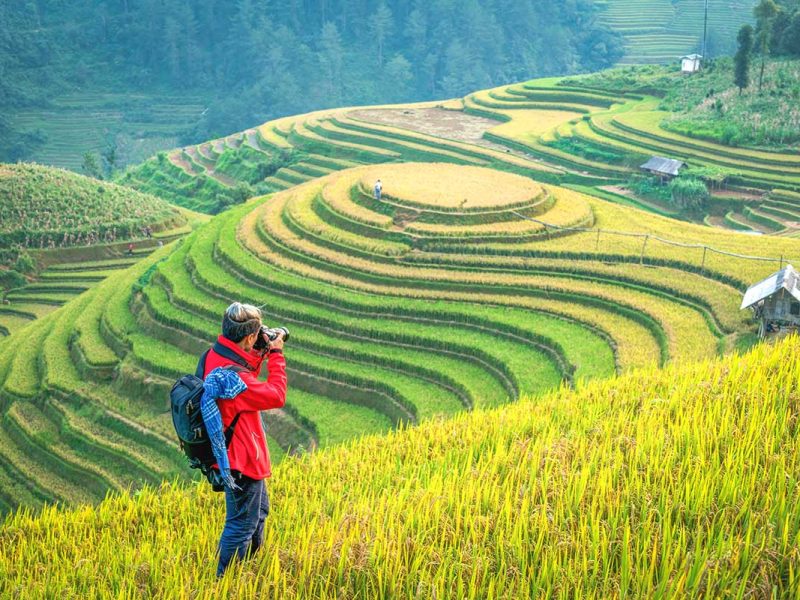 A photographer making photos during a trekking through the terraced rice fields of Mu Cang Chai
