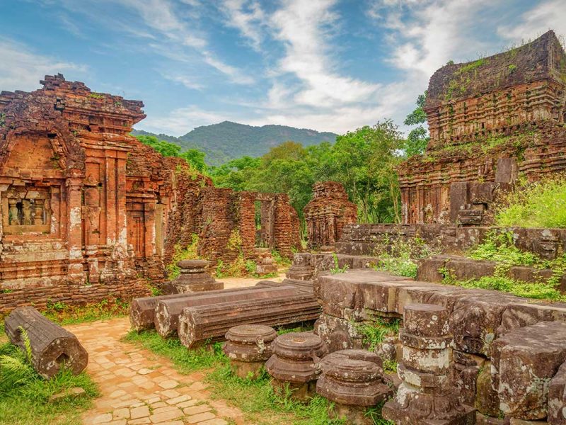 Ancient brick temples surrounded by jungle at My Son Sanctuary – one of the best day trips from Hoi An for history and culture lovers.