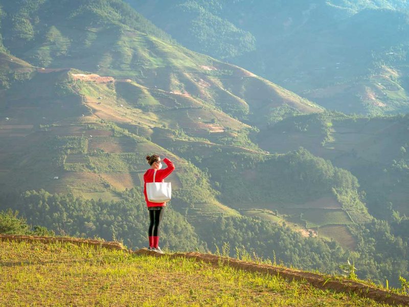 Viewpoint overlooking San Nhu Village in Mu Cang Chai with a traveler enjoying the mountain landscape