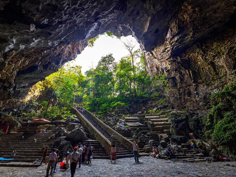 Massive entrance of Huong Tich Cave with steps leading down into the sacred site
