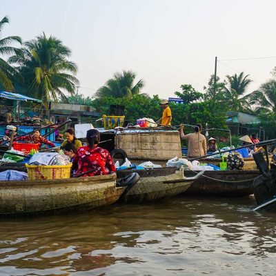 Busy river scene with sellers and buyers exchanging goods at Phong Dien Floating Market near Can Tho, Vietnam.