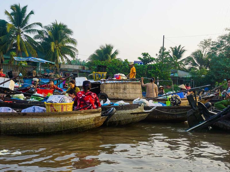 Busy river scene with sellers and buyers exchanging goods at Phong Dien Floating Market near Can Tho, Vietnam.