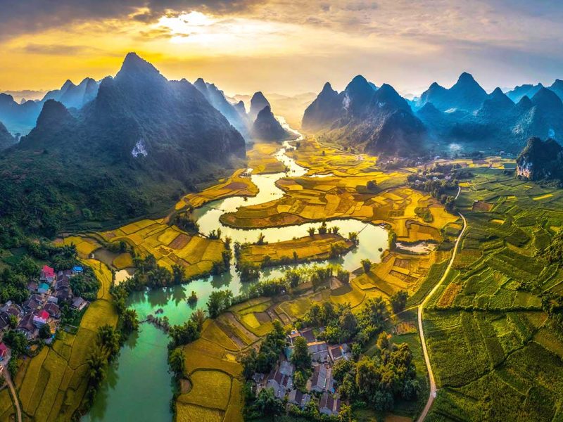 Aerial view of Phong Nam Valley with a river running through a valley surrounded by rice fields and mountains.