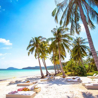Palm trees and pure white sand with lounge chairs at Bai Sao Beach on Phu Quoc Island.