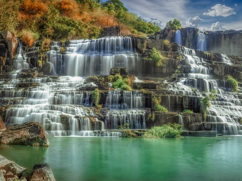 Pongour Waterfall in the dry season near Dalat, showing layered waterfalls surrounded by forested hills and seasonal colors.