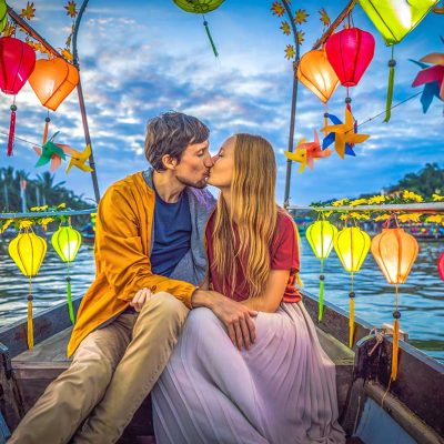 A romantic couple celebrating their honeymoon in Vietnam on a boat tour over the Thon Bon River in Hoi An