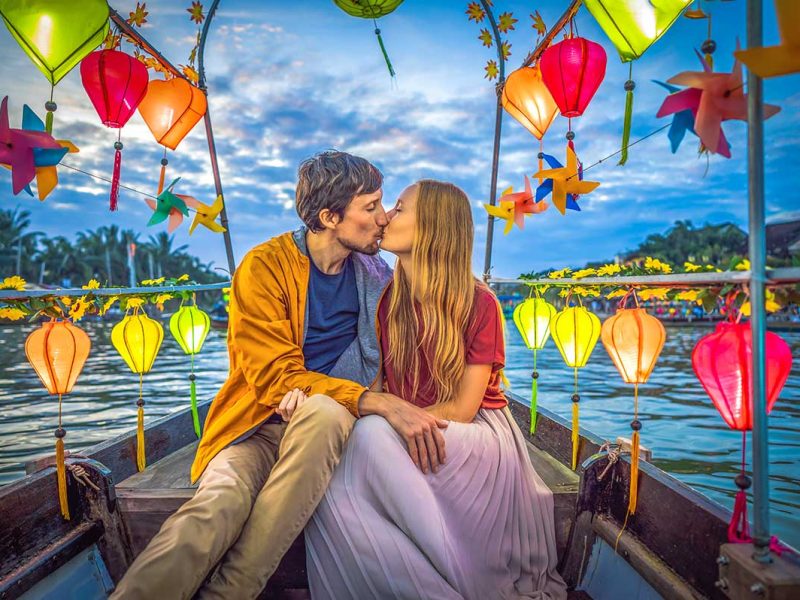 A romantic couple celebrating their honeymoon in Vietnam on a boat tour over the Thon Bon River in Hoi An