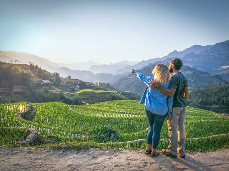 A couple making a romantic trekking in Sapa through terrace rice fields in Vietnam