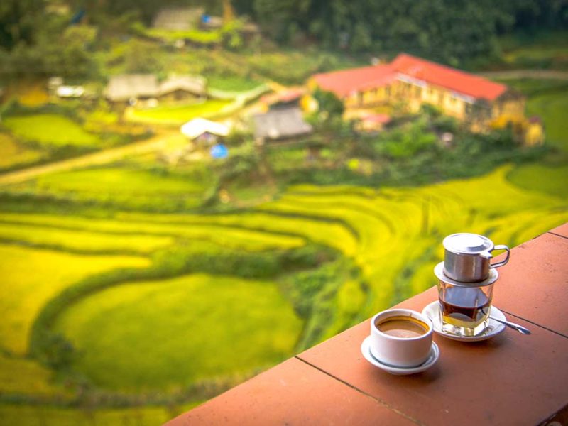 A Vietnamese coffee cup with phin filter standing on a table at a coffee shop in Sapa with amazing views over the rice fields