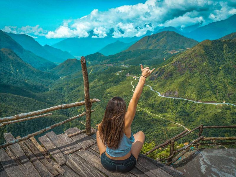 A girl sitting on a wooden platform serving as viewpoint over Tram Ton pass