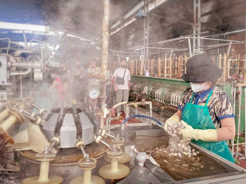 Worker processing silk cocoons inside a local silk factory visited on the Dalat to Mui Ne tour, showing traditional silk production methods