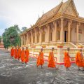 Soc Trang tours with Khmer monks walking past an ornate pagoda in southern Vietnam
