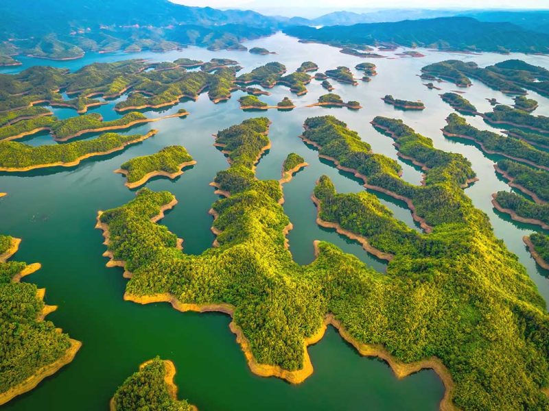 ta dung lake 4 A high-altitude aerial image showcasing the vast, island-filled waters of Ta Dung Lake, nestled within the rolling hills of Dak Nong.
