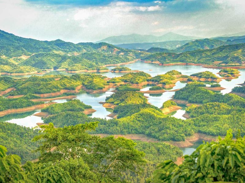 Wide panoramic view of Ta Dung Lake with dozens of green islands surrounded by water, often called the “Halong Bay of the Central Highlands”