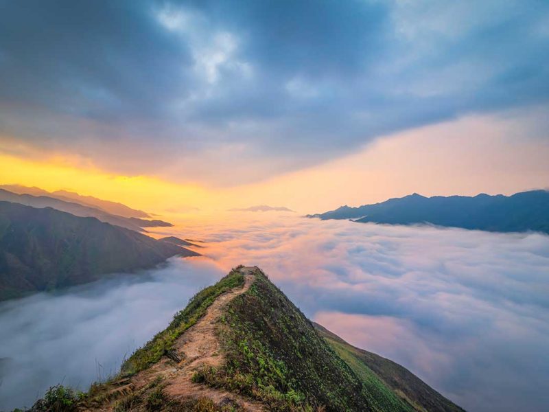Famous Dinosaur Spine of Ta Xua - A dirt path leading over the edge of the mountain with valley view that is full of clouds