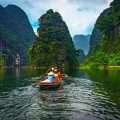 a rowing boat going over the river between high karst mountains in Trang An, Ninh Binh