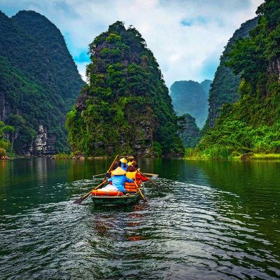 a rowing boat going over the river between high karst mountains in Trang An, Ninh Binh