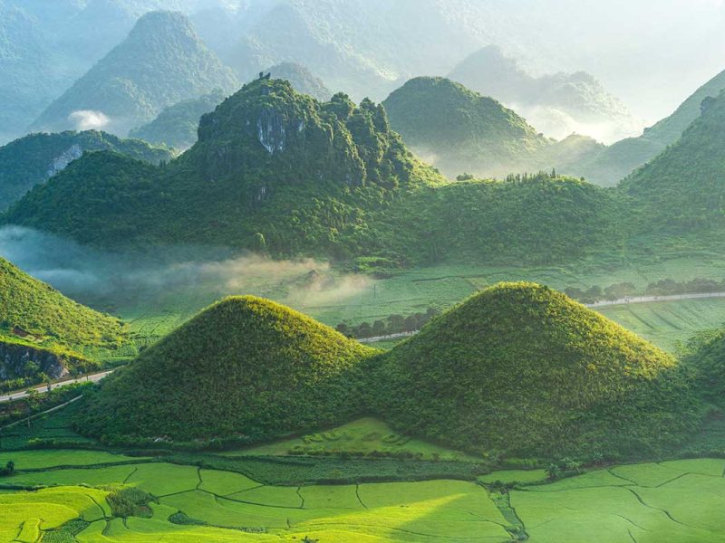A panoramic view of the Twin Mountains in Quan Ba, Ha Giang, surrounded by lush green rice fields.