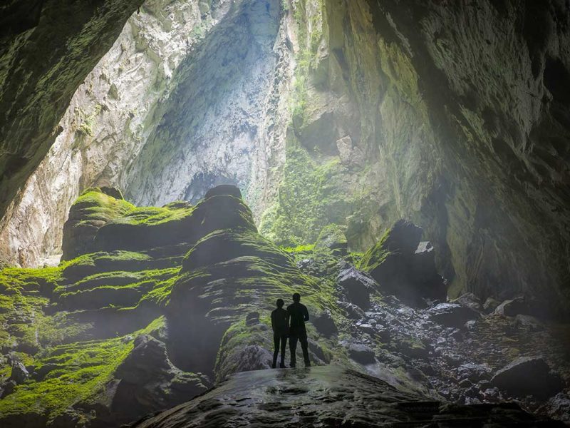 vietnam tours phong nha caving trekking 1 Explorers standing inside a giant cave in Phong Nha-Ke Bang National Park – an adventurous activity featured in Vietnam tours.