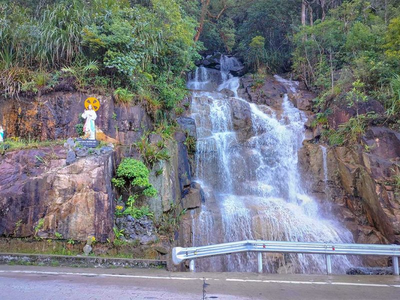 Small roadside waterfall flowing down rocky cliffs along Khanh Le Pass, a natural highlight on the Dalat to Nha Trang route