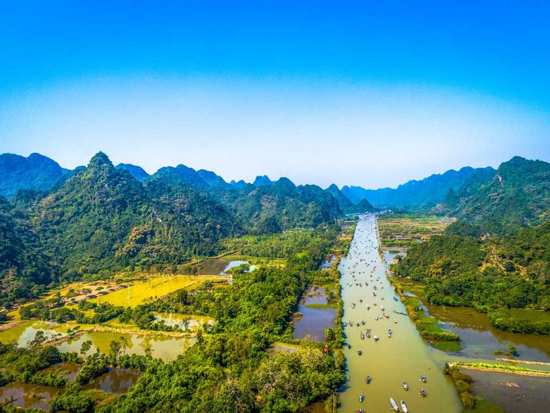 Yen Stream Boats to Perfume Pagoda: Boats filled with pilgrims and tourists navigate the Yen Stream, a tributary of the Red River, on their way to the Perfume Pagoda.